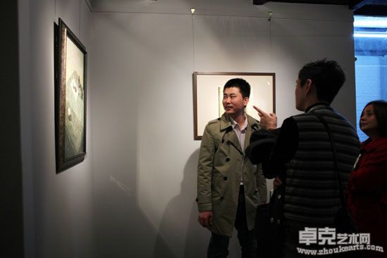 嘉德在线总裁陆昂（右一）和年轻艺术家品评画作