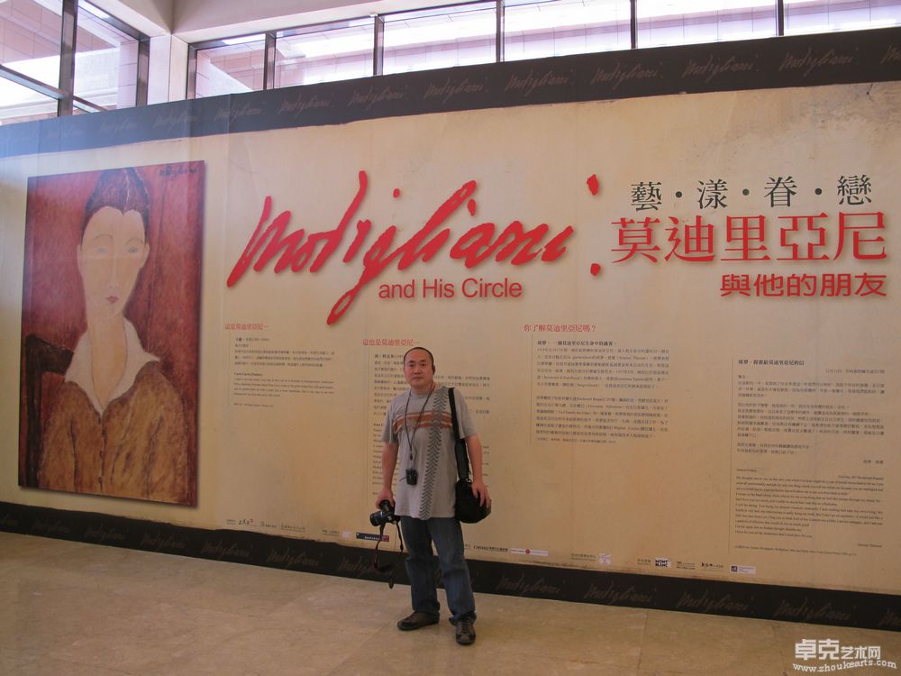 2011年6月30日，刘子建在台北市立美术馆莫迪尼亚画展招贴前留影