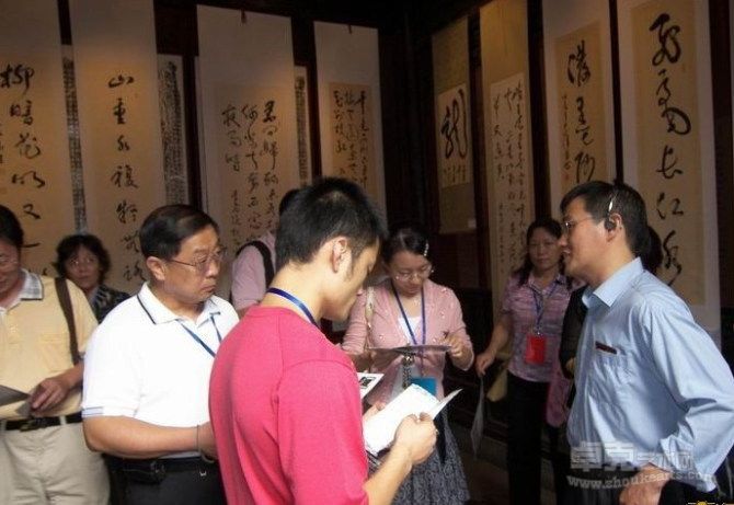李伟华为在杭州举行的全国“全民终身活动周”的嘉宾介绍书法展。背景为李伟华书法作品